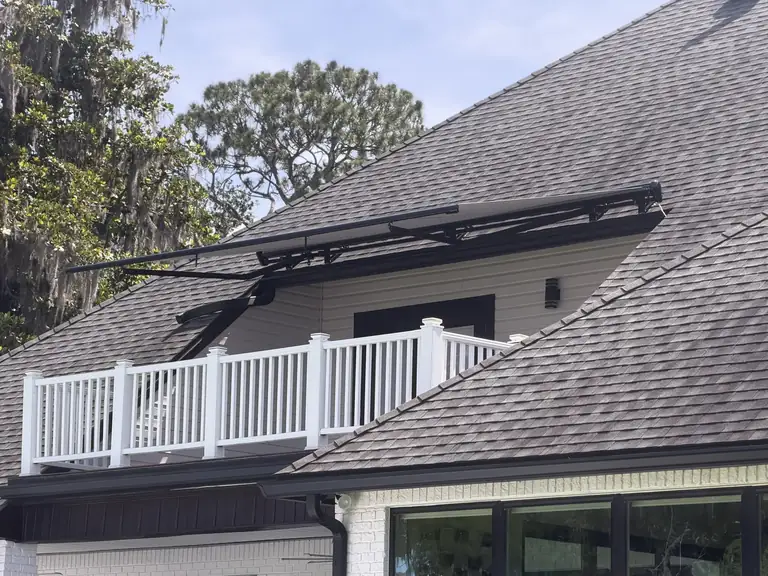 Motorized retractable awning on a custom roof-bracket mount at a Fruit Cove, Florida home