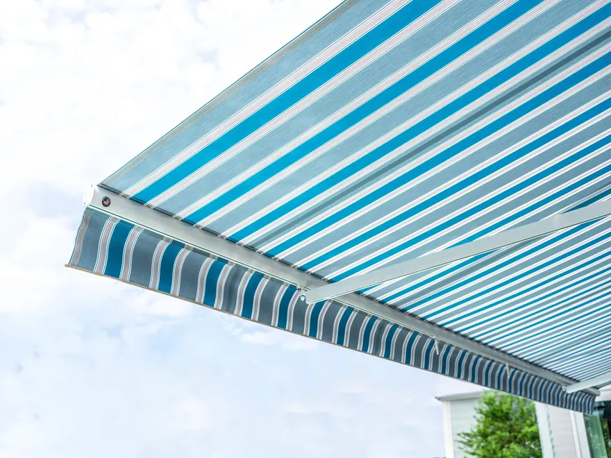 White-frame motorized retractable awning shading a Florida patio with open sky above