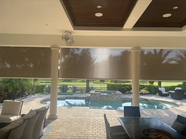 Open-roller motorized screens between residential pool columns
