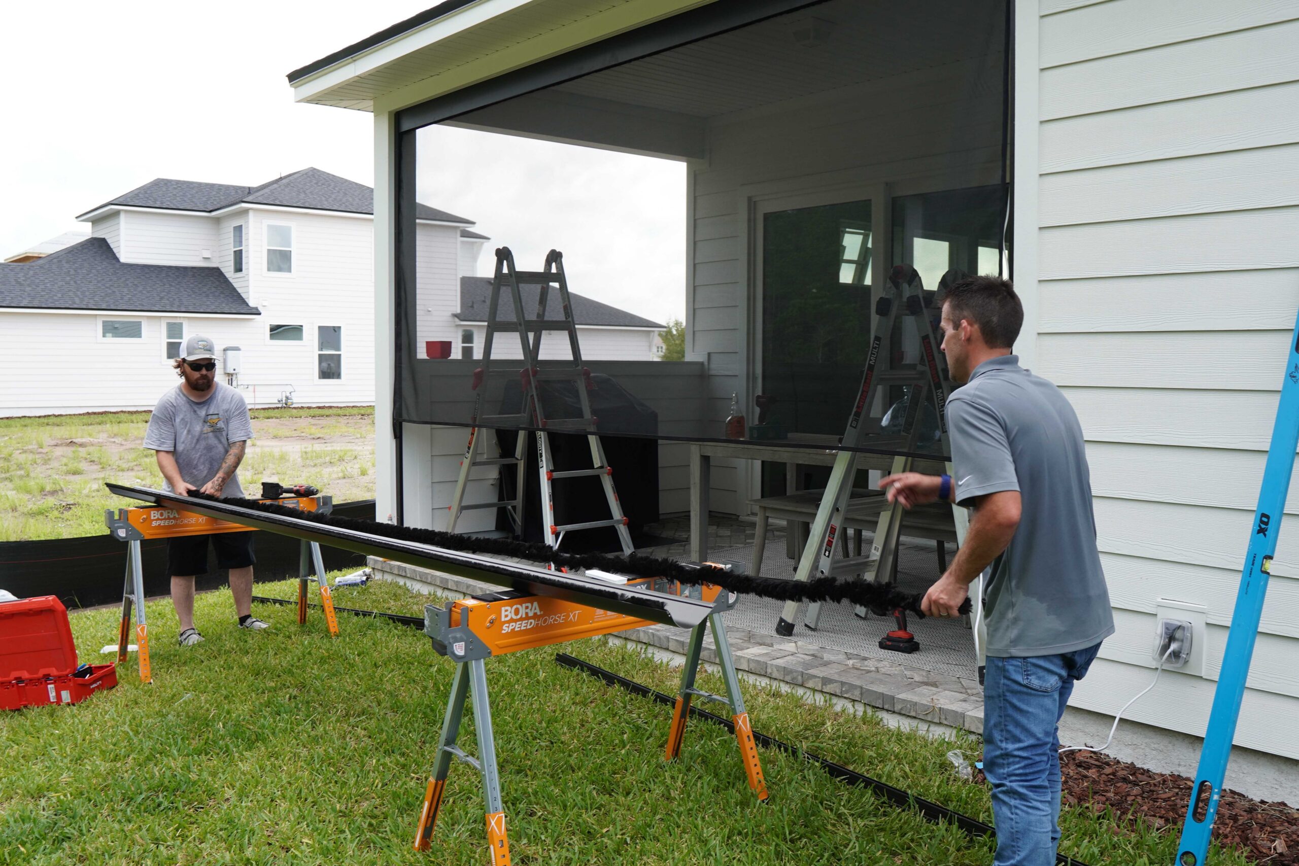 Cheetah Screens technicians fitting a motorized retractable screen track at a Jacksonville home